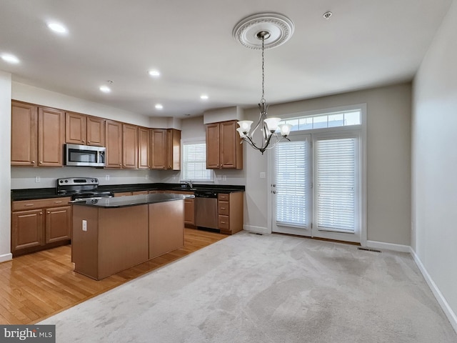 kitchen with a kitchen island, light hardwood / wood-style floors, stainless steel appliances, pendant lighting, and a notable chandelier