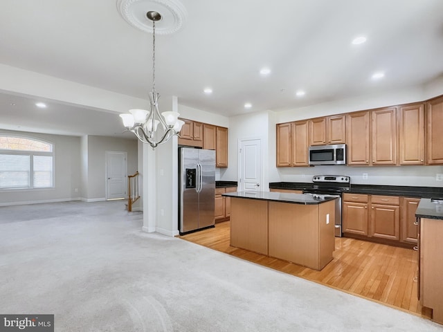 kitchen with hanging light fixtures, appliances with stainless steel finishes, light hardwood / wood-style floors, a notable chandelier, and a center island