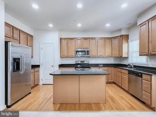 kitchen with light hardwood / wood-style floors, stainless steel appliances, sink, and a kitchen island