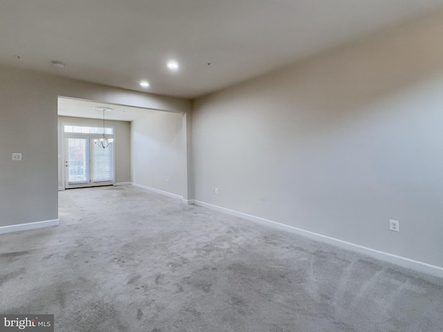 unfurnished room featuring an inviting chandelier and carpet