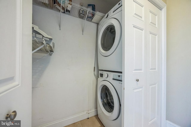 clothes washing area featuring stacked washing maching and dryer and light tile patterned floors