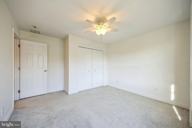 unfurnished bedroom with a closet, light colored carpet, and ceiling fan