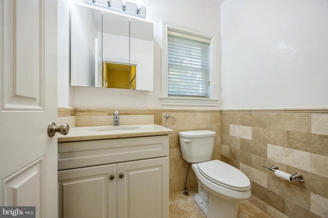 bathroom with tile walls, vanity, toilet, and tile patterned flooring