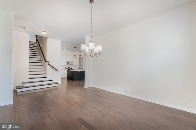 spare room with a chandelier and dark hardwood / wood-style flooring