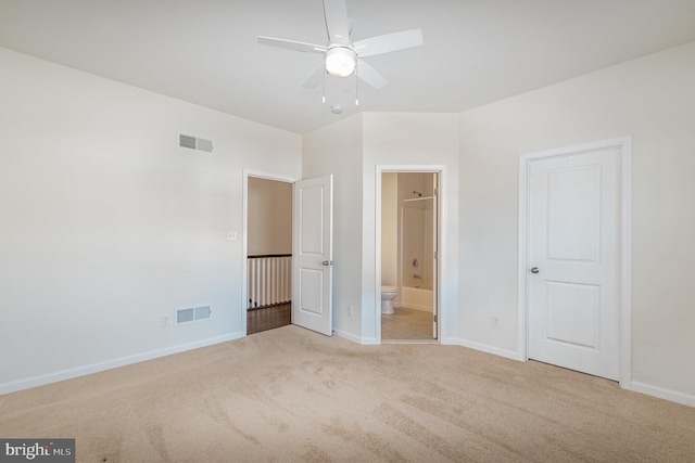 unfurnished bedroom with ensuite bathroom, carpet flooring, and ceiling fan