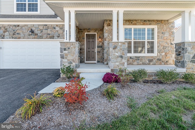 view of exterior entry featuring covered porch and a garage