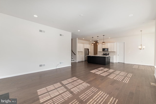 unfurnished living room featuring dark hardwood / wood-style flooring and an inviting chandelier