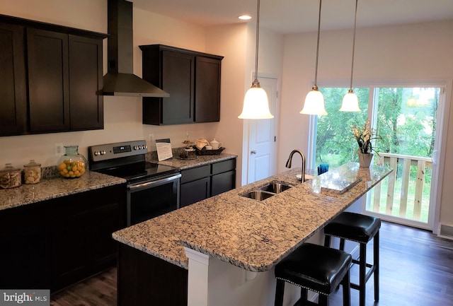 kitchen with wall chimney exhaust hood, sink, stainless steel electric stove, and a center island with sink