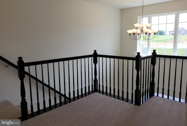 staircase featuring carpet and a chandelier