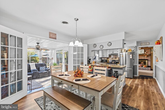 dining area with hardwood / wood-style floors, sink, ceiling fan with notable chandelier, and a fireplace