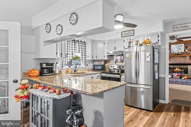 kitchen with light hardwood / wood-style flooring, kitchen peninsula, stainless steel appliances, and sink