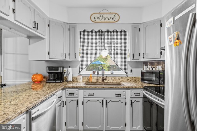 kitchen featuring stainless steel appliances, sink, and light stone counters