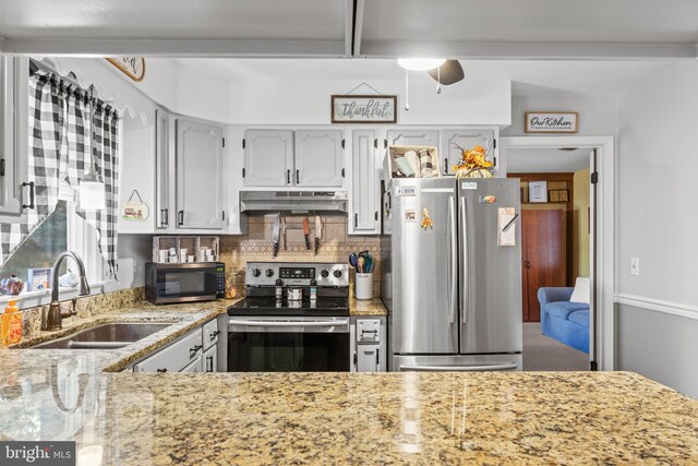 kitchen with light stone counters, stainless steel appliances, beamed ceiling, and sink