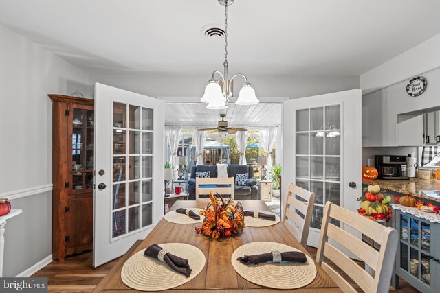 dining space with french doors, wood-type flooring, and ceiling fan with notable chandelier