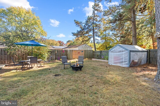 view of yard with an outdoor fire pit and a storage unit