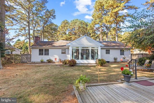 rear view of property featuring a wooden deck, a yard, and a sunroom