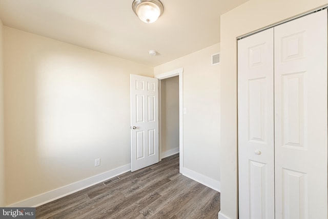 unfurnished bedroom featuring a closet and dark hardwood / wood-style floors