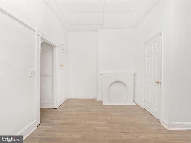 unfurnished living room featuring light hardwood / wood-style flooring and a paneled ceiling