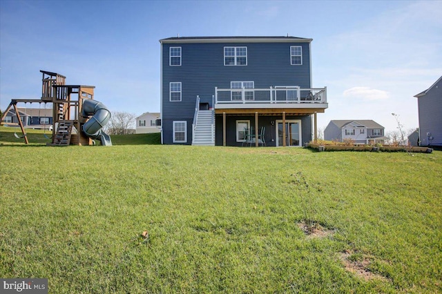 back of house featuring a playground, a deck, and a yard