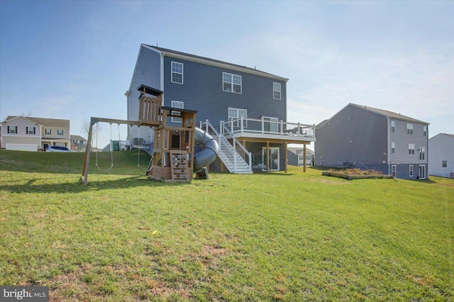 rear view of property featuring a lawn, a wooden deck, and a playground