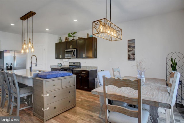 kitchen with pendant lighting, a center island with sink, sink, light hardwood / wood-style flooring, and stainless steel appliances