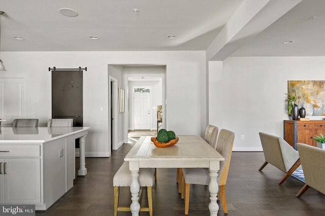 dining room with a barn door and dark hardwood / wood-style floors