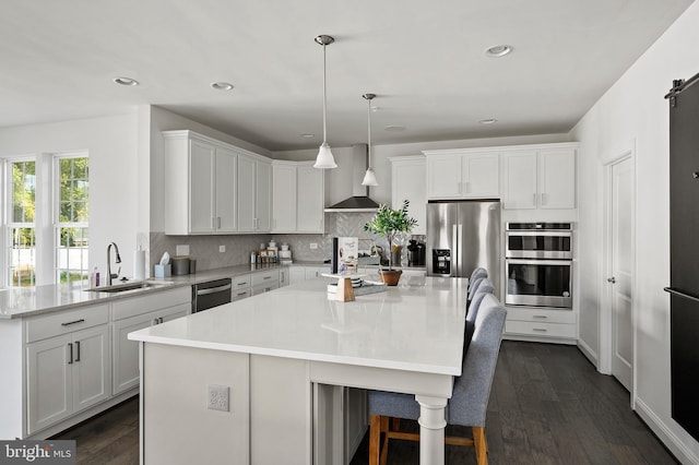 kitchen with wall chimney exhaust hood, pendant lighting, a center island, and stainless steel appliances