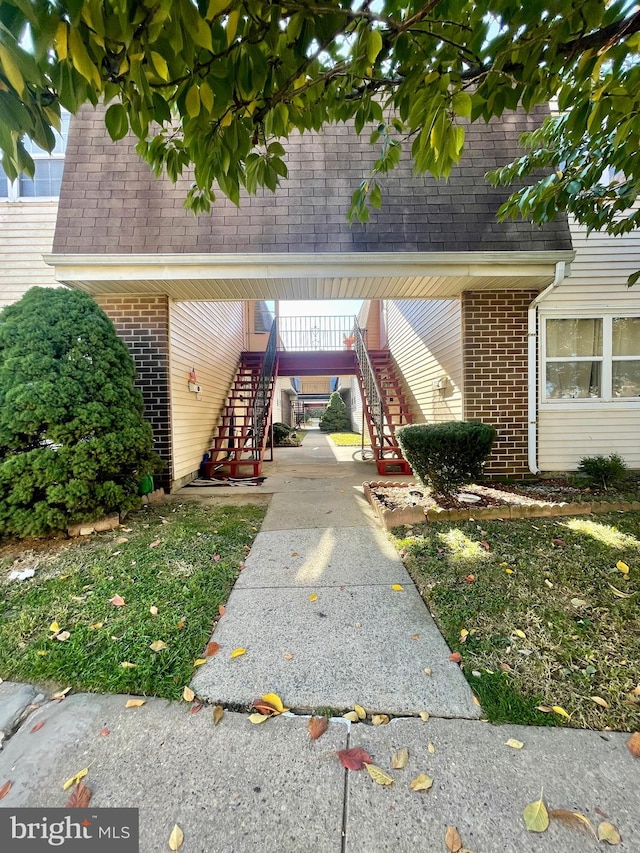 view of exterior entry featuring brick siding and a shingled roof