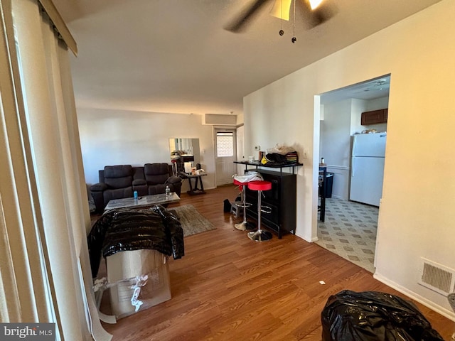 living area featuring wood finished floors, visible vents, and ceiling fan