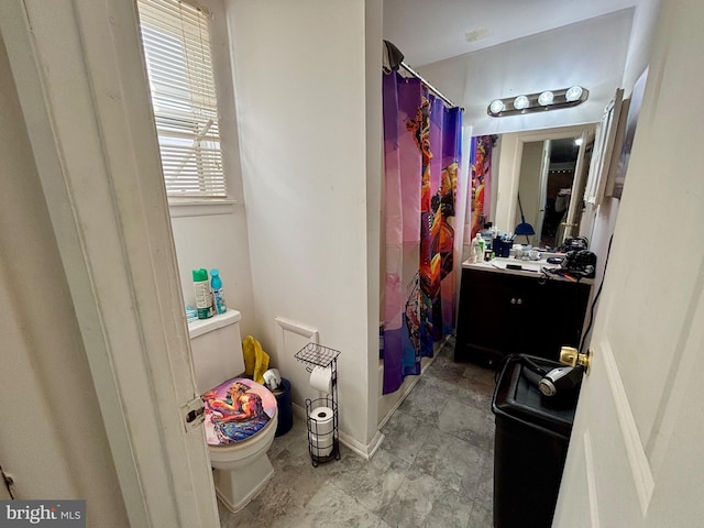 bathroom featuring vanity, a shower with shower curtain, toilet, and baseboards