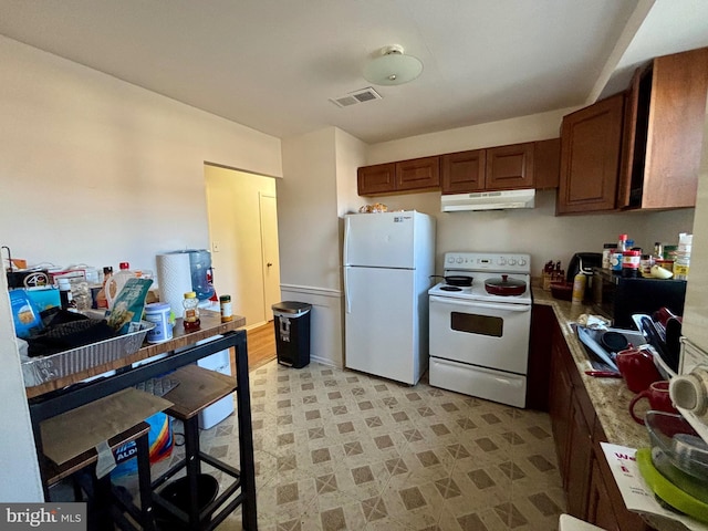 kitchen featuring under cabinet range hood, light floors, light countertops, white appliances, and a sink