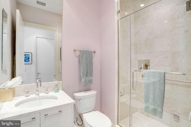 bathroom featuring toilet, an enclosed shower, and vanity