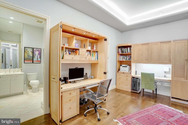 office space featuring built in desk, sink, and hardwood / wood-style floors