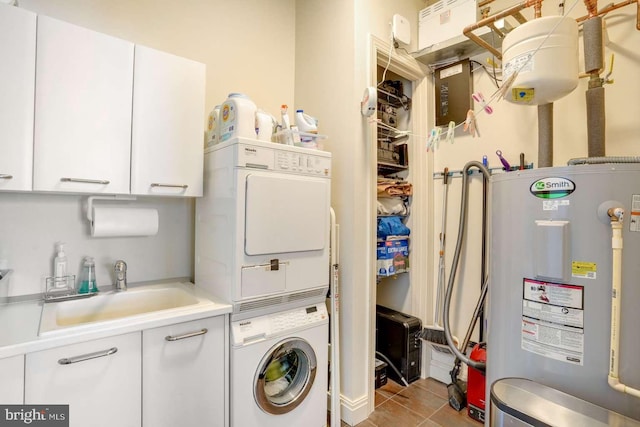 washroom with stacked washer and clothes dryer, electric water heater, sink, light tile patterned floors, and cabinets