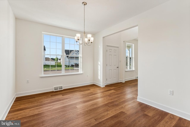 unfurnished dining area featuring dark hardwood / wood-style floors and an inviting chandelier