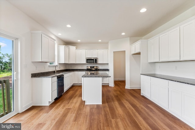 kitchen featuring light hardwood / wood-style flooring, white cabinets, stainless steel appliances, and dark stone counters