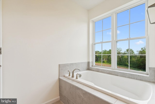 bathroom with a relaxing tiled tub and a healthy amount of sunlight