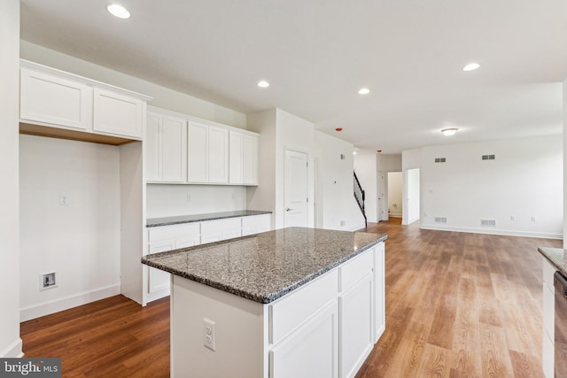 kitchen featuring light hardwood / wood-style floors, white cabinets, dark stone countertops, and a center island