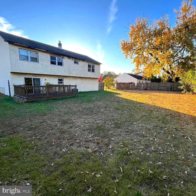 back of property featuring a wooden deck and a lawn