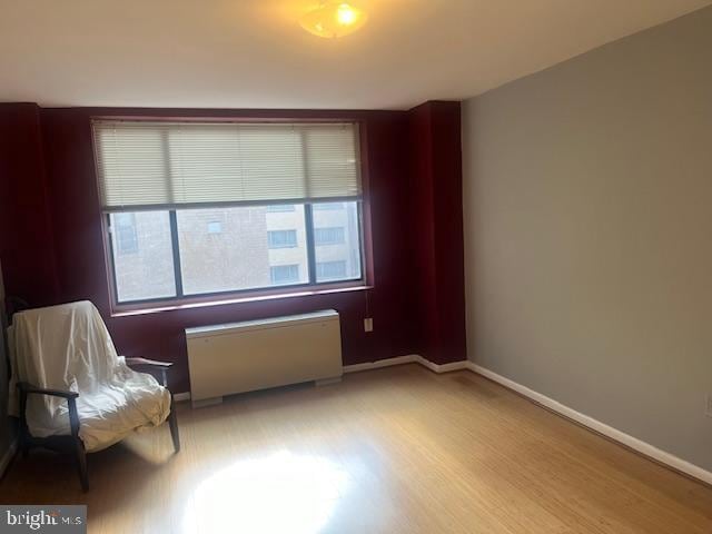 unfurnished room featuring radiator heating unit and light wood-type flooring