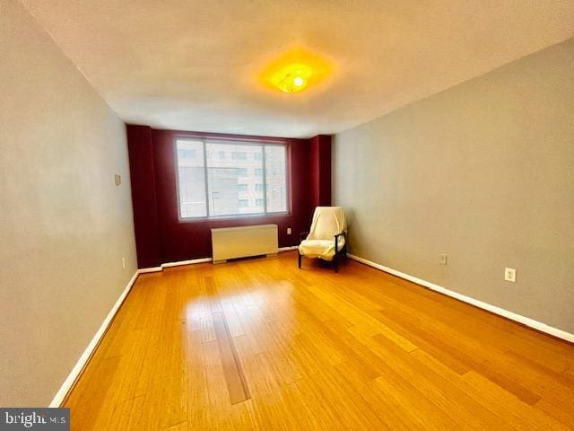 unfurnished room featuring wood-type flooring and radiator heating unit