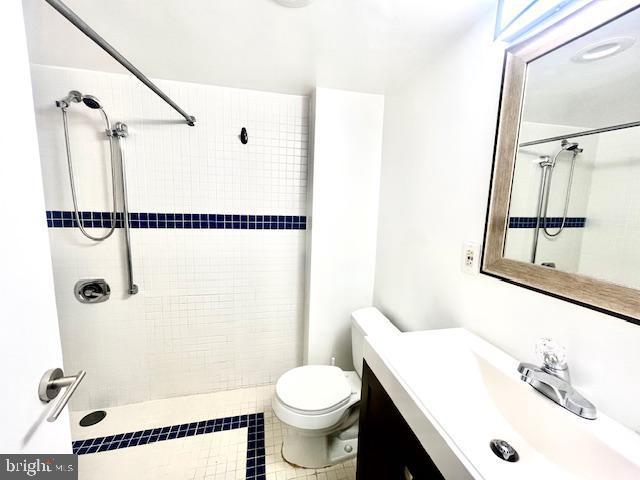 bathroom featuring tile patterned floors, toilet, vanity, and tiled shower