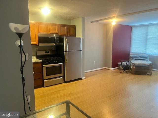 kitchen featuring light stone counters, stainless steel appliances, and light hardwood / wood-style flooring