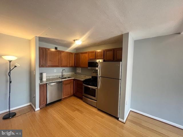 kitchen with sink, light hardwood / wood-style flooring, a textured ceiling, and appliances with stainless steel finishes