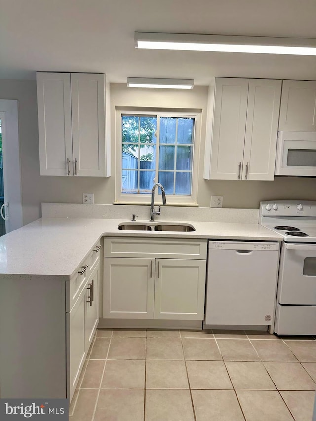 kitchen featuring white appliances, sink, kitchen peninsula, white cabinets, and light tile patterned floors