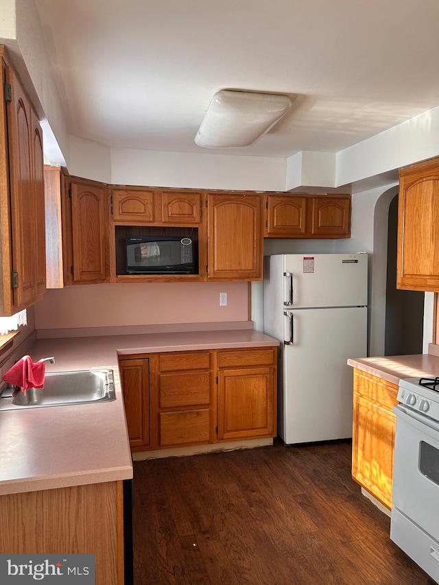 kitchen with dark hardwood / wood-style floors, sink, and white appliances