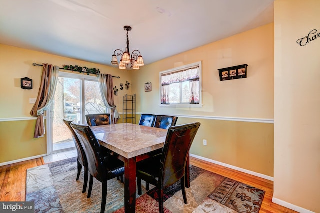 dining space featuring wood-type flooring and a notable chandelier