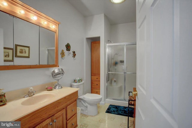 bathroom featuring vanity, toilet, and a shower with shower door