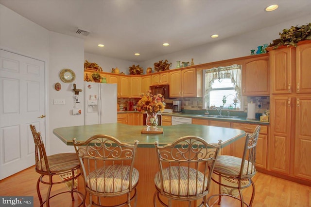 kitchen with white appliances, sink, light wood-type flooring, a center island, and decorative backsplash