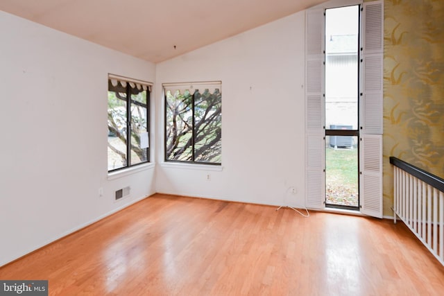 unfurnished room with light wood-type flooring and lofted ceiling